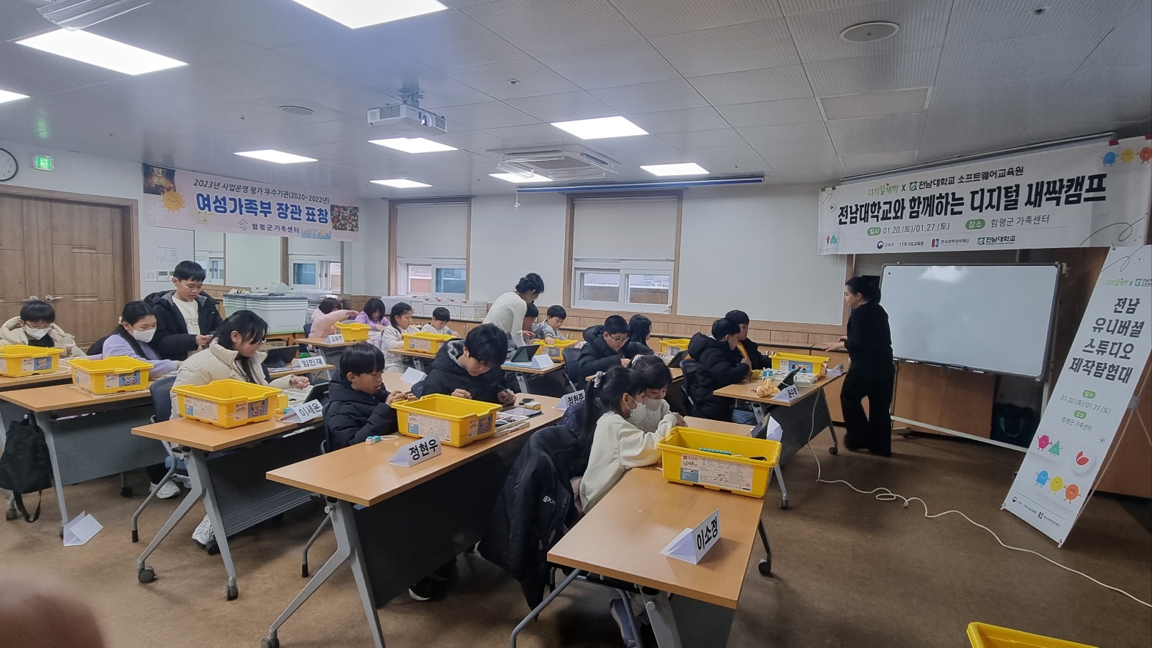 전남대학교와 함께하는 디지털 새싹캠프에서 전남 유니버셜 스튜디오 제작탐험대 활동을 위한 설명을 하고, 아이들은 경청하며 활동하고 있다.